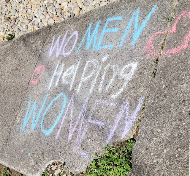 Chalk drawing states Women Helping Women on sidewalk