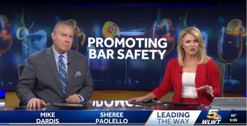 WLWT News 5 anchors Mike Dardis and Sheree Paolello on set discussing a "Promoting Bar Safety" segment, with a graphic showing cocktail glasses in the background.