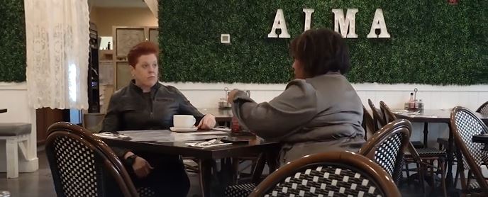 Host Michelle and Women Helping Women CEO Kristin Shrimplin sitting together at a local coffee shop during a video interview segment