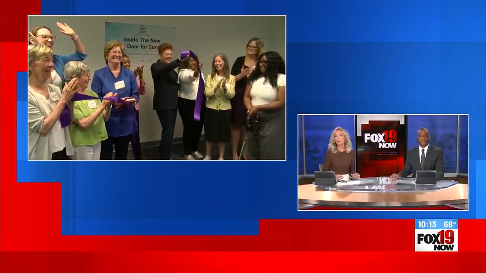 A group of community leaders and advocates gather together to cut a celebratory ribbon, marking the opening ceremony of the new Women Helping Women 24/7 hotline hub.